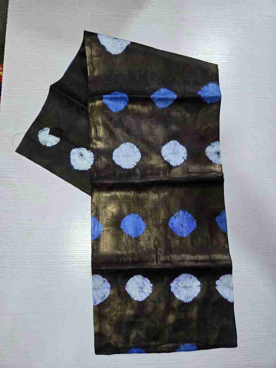 Hand-dyed Adire Kampala fabric with rows of bold royal blue and stark white tie-dye circular bursts on a metallic bronze-sheen dark background