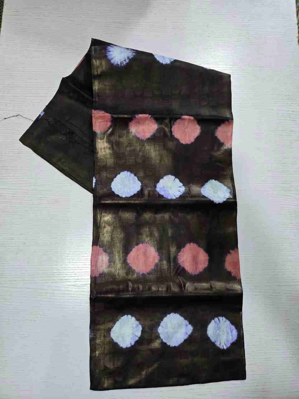 Textured tie-dye Kampala fabric featuring alternating rows of soft rose-pink and ice-blue circular bursts on a metallic dark bronze geometric jacquard base