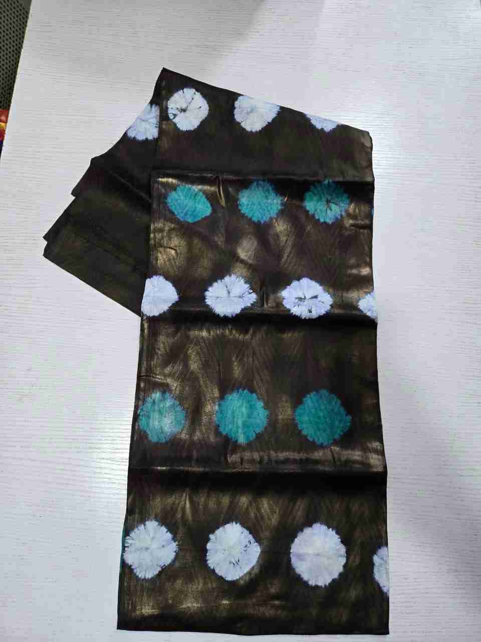 Traditional African Kampala fabric adorned with alternating rows of deep teal-green and stark white circular tie-dye bursts over a dark bronze chevron-textured base