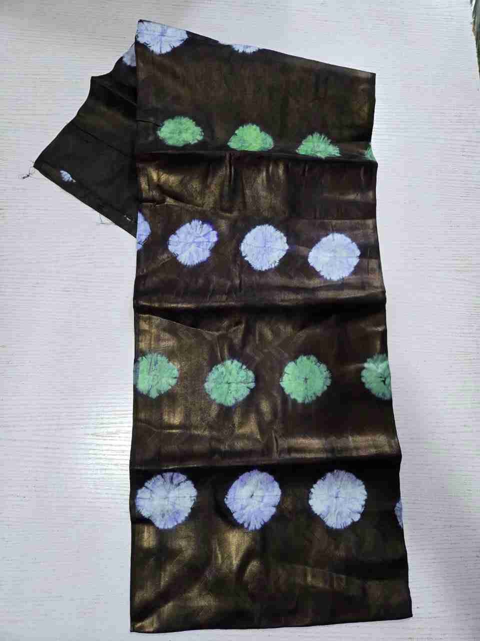 Traditional African Kampala fabric displaying rows of lime-green and pale lavender tie-dye circle bursts against a dark bronze textured background